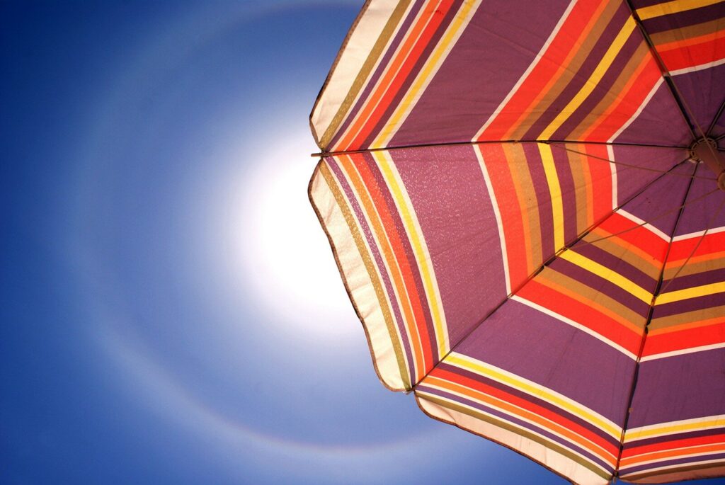 El sol brilla detrás de una sombrilla colorida